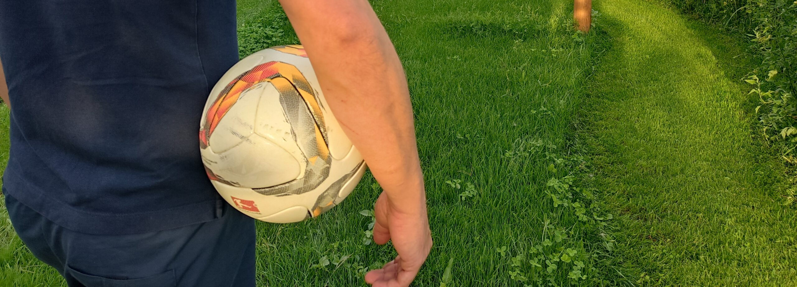 Mann mit Ball unterm Arm von hinten_